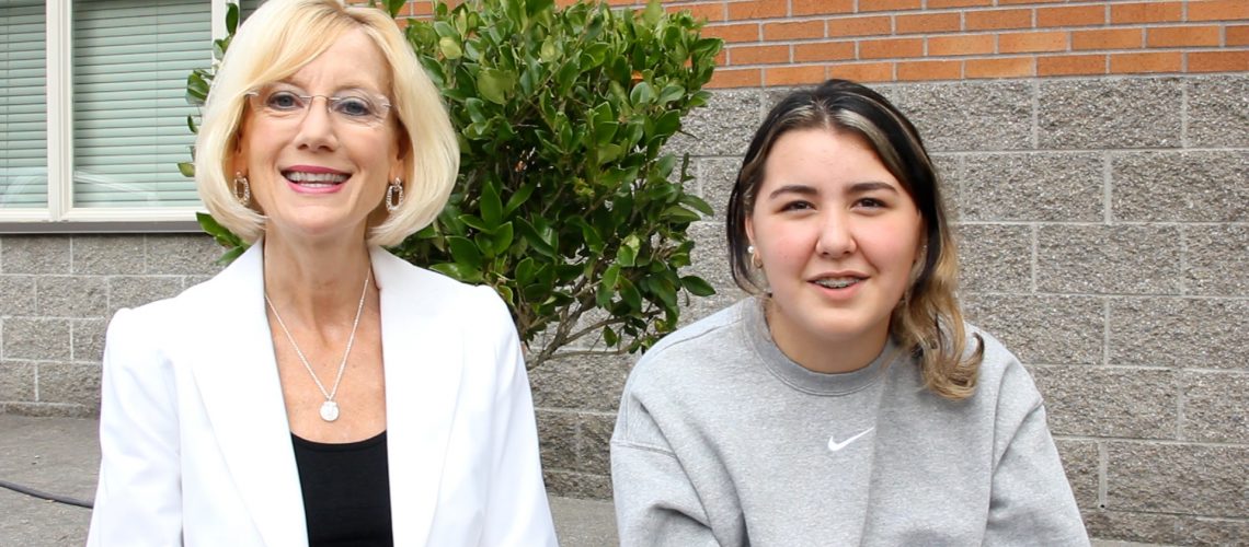 Superintendent Mary (left) and CCMS student Morgan (right) sit outdoors facing the camera.
