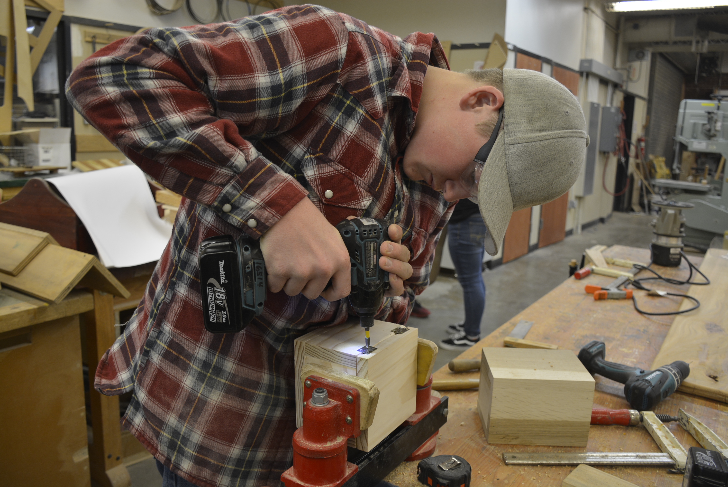 Student uses nail gun to assemble wooden box