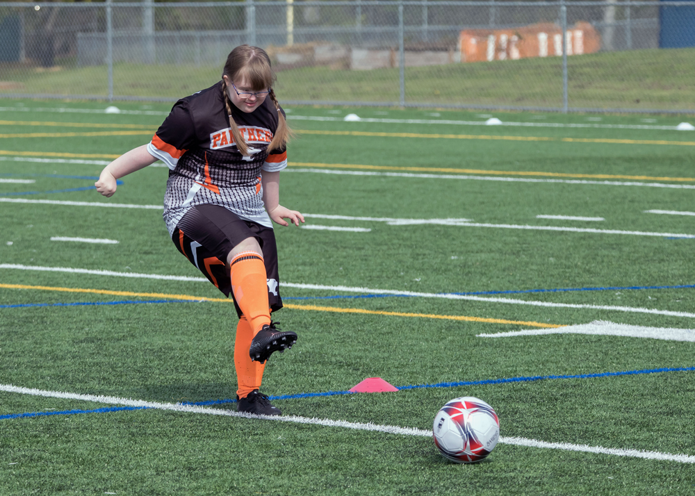 WHS Unified soccer player Suzanne kicks the ball on the turf