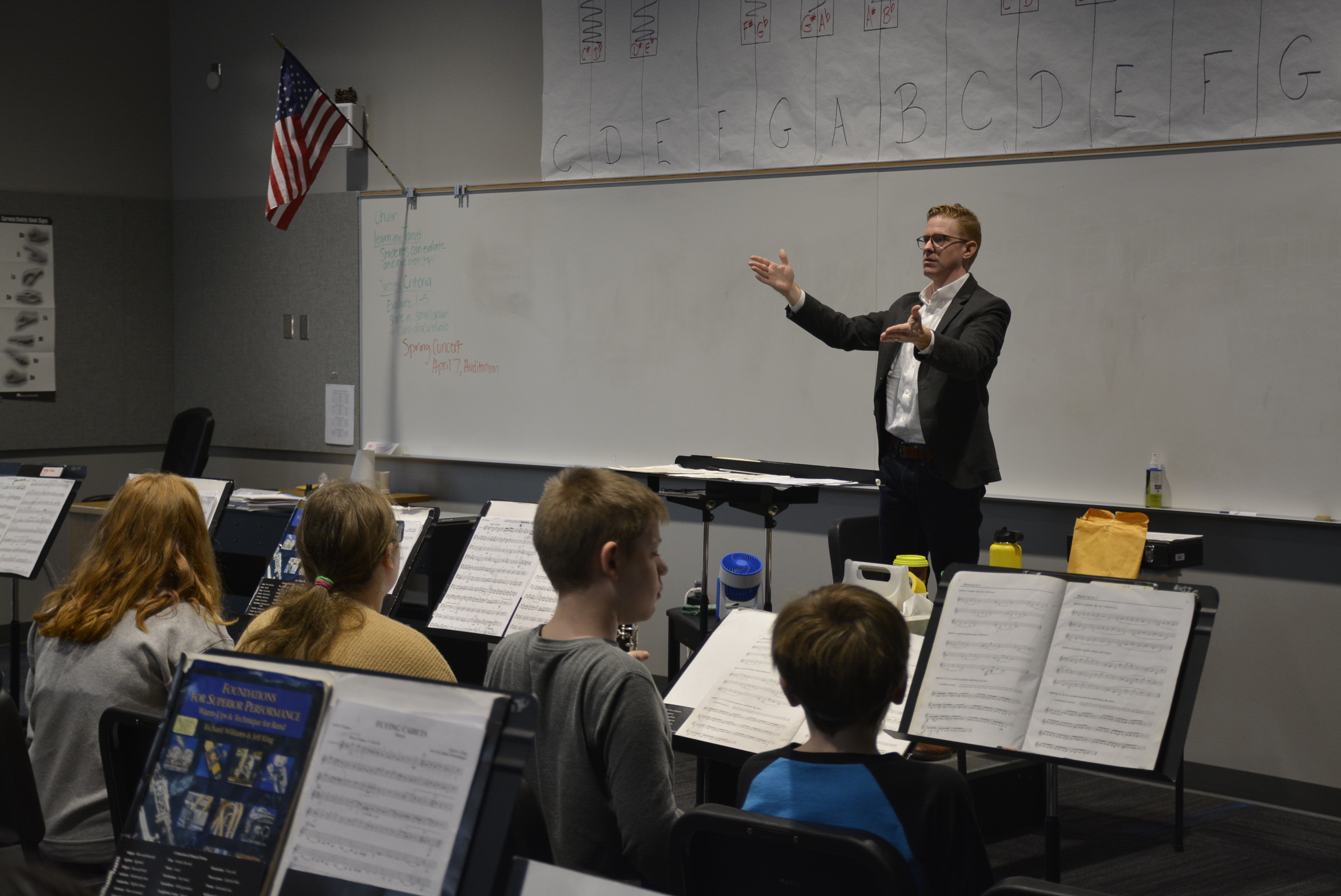 Guest conductor working with students in the JMS band, with students looking at sheet music on stands