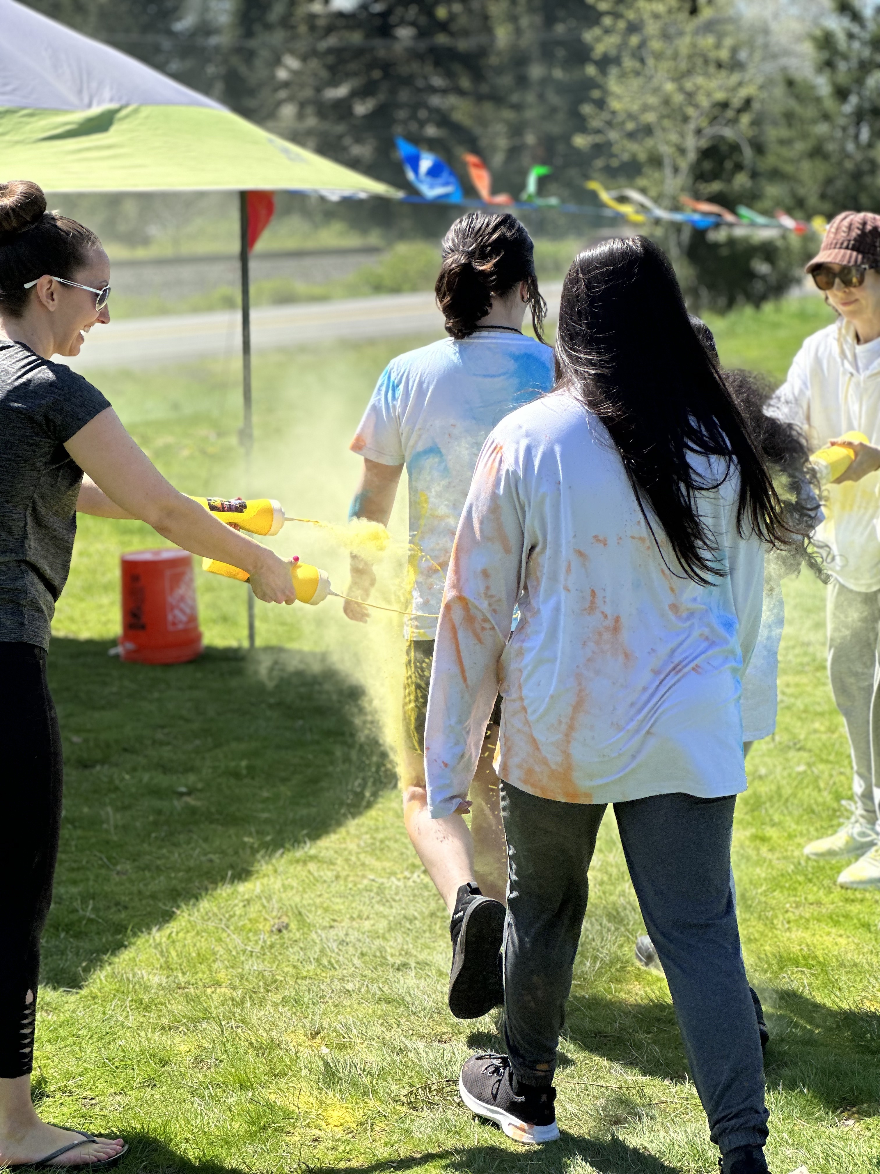 Student runs through two volunteers who spray them with yellow food safe dye