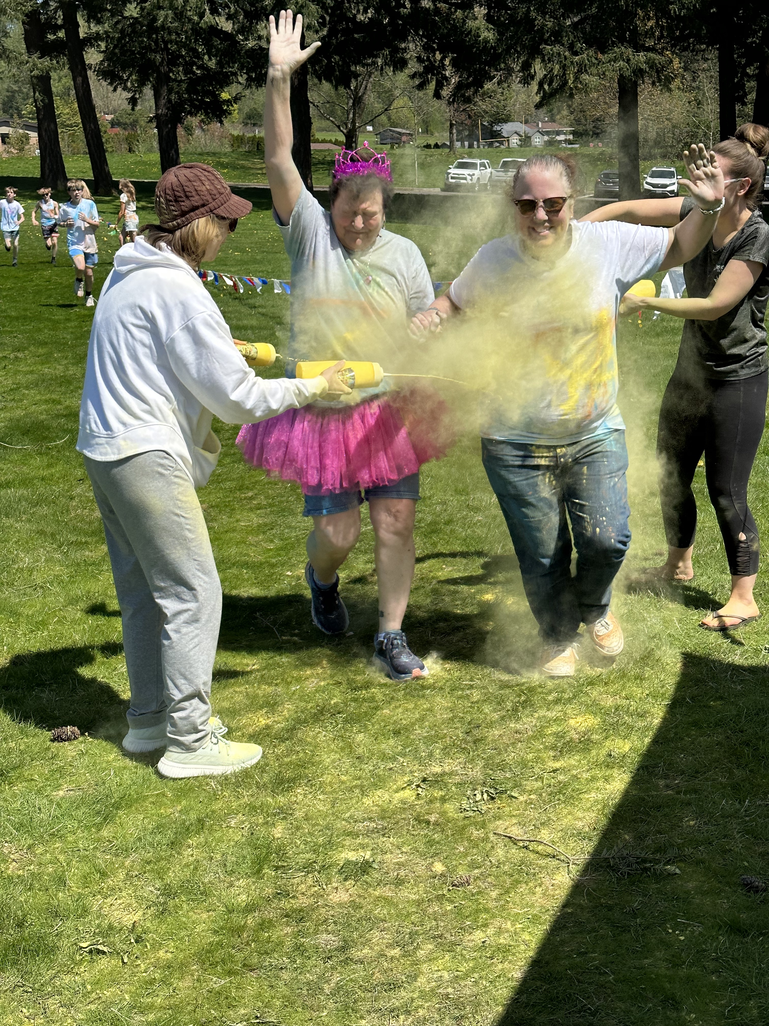 Staff members run past volunteers spraying yellow dye