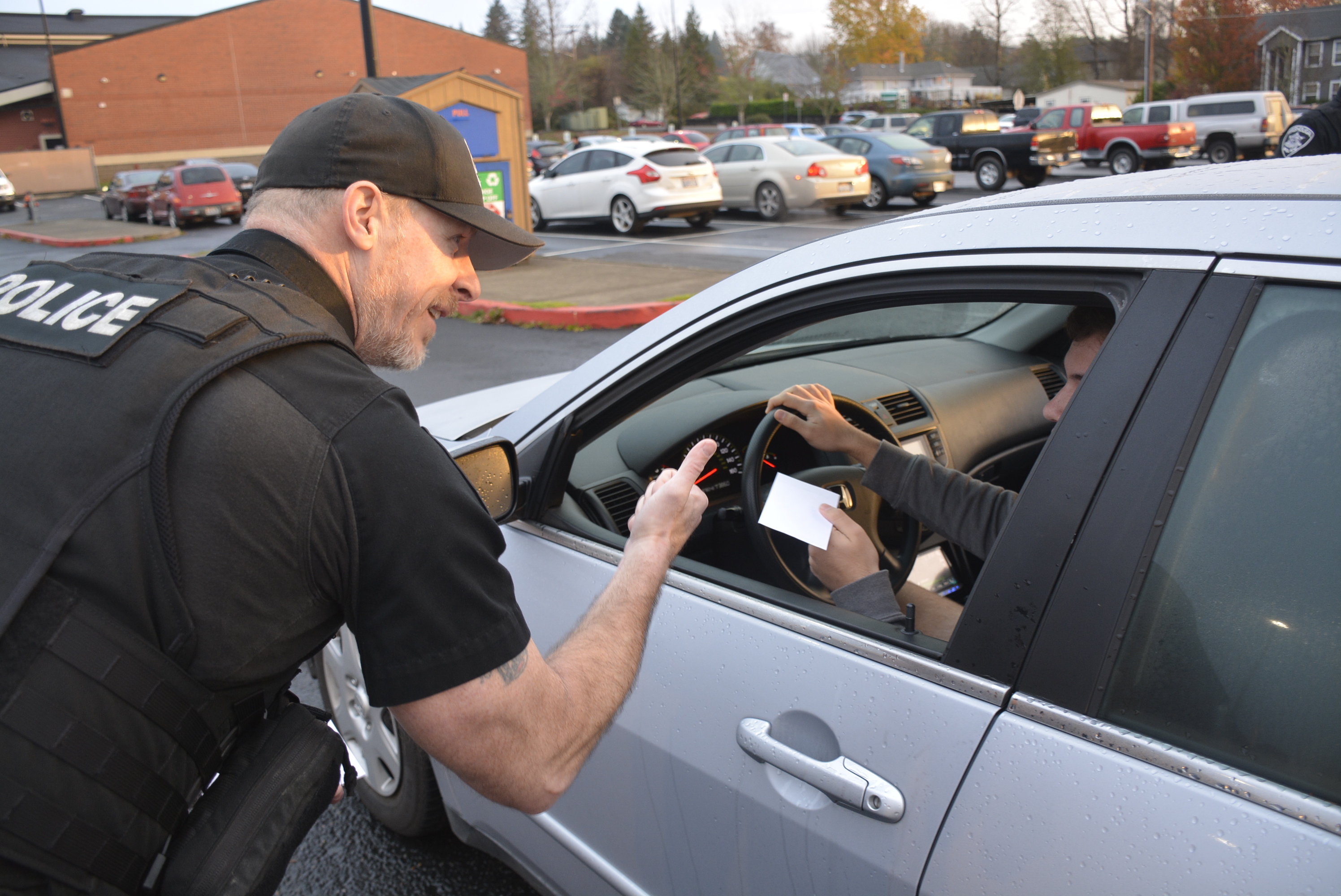 Washougal Police Officer gives thumbs up to teen driver for wearing seatbelt, and provides gift card to student driving car