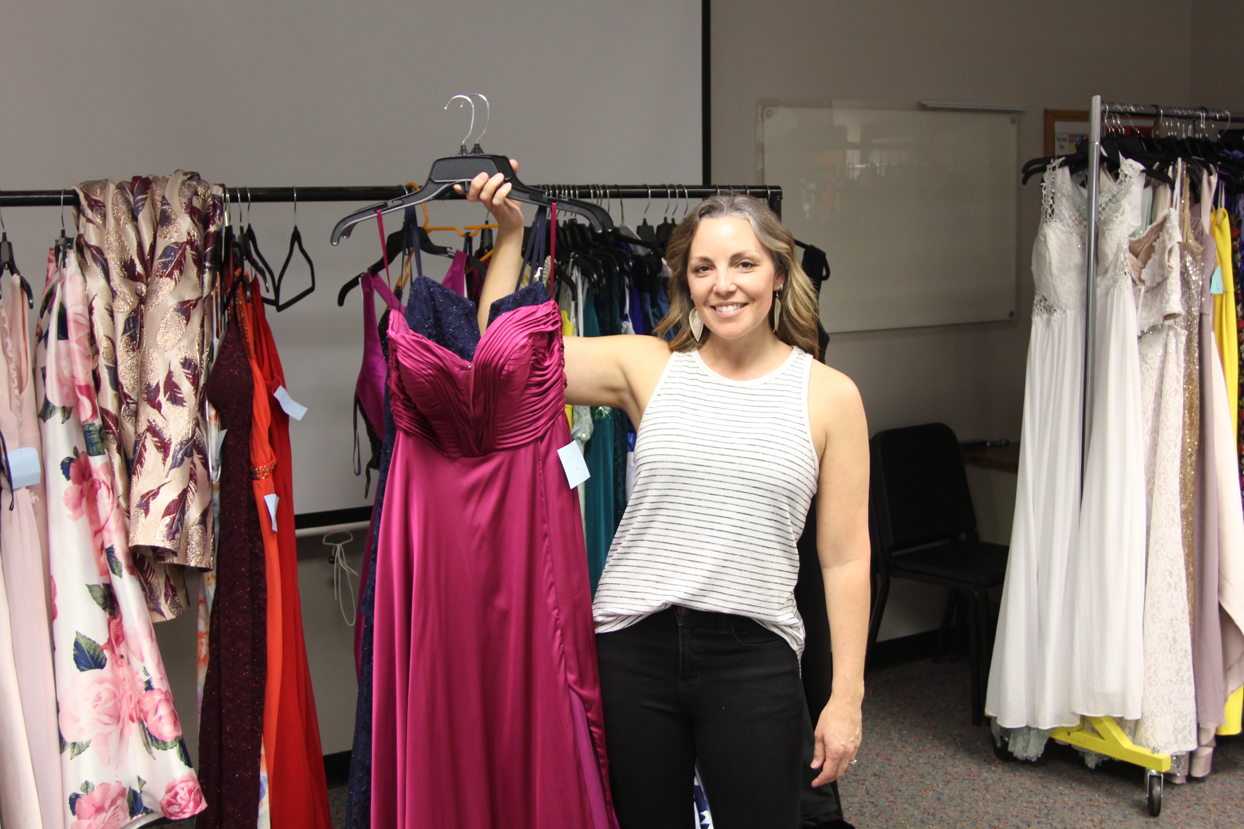 Tara Poulsen poses with a gown donated for the giving gown gala, with other gowns in the background