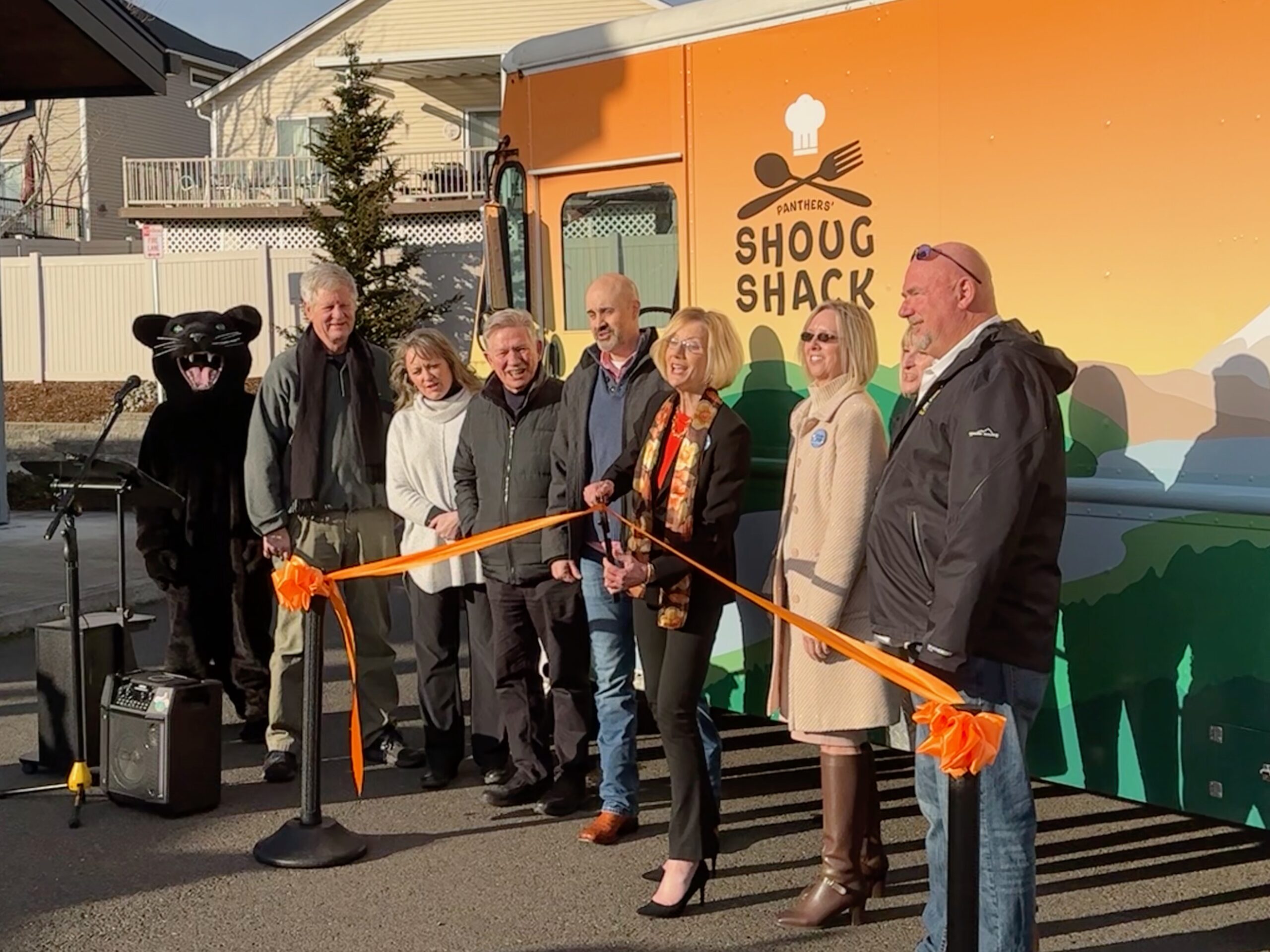 Board members and guests cut ribbon in front of food truck