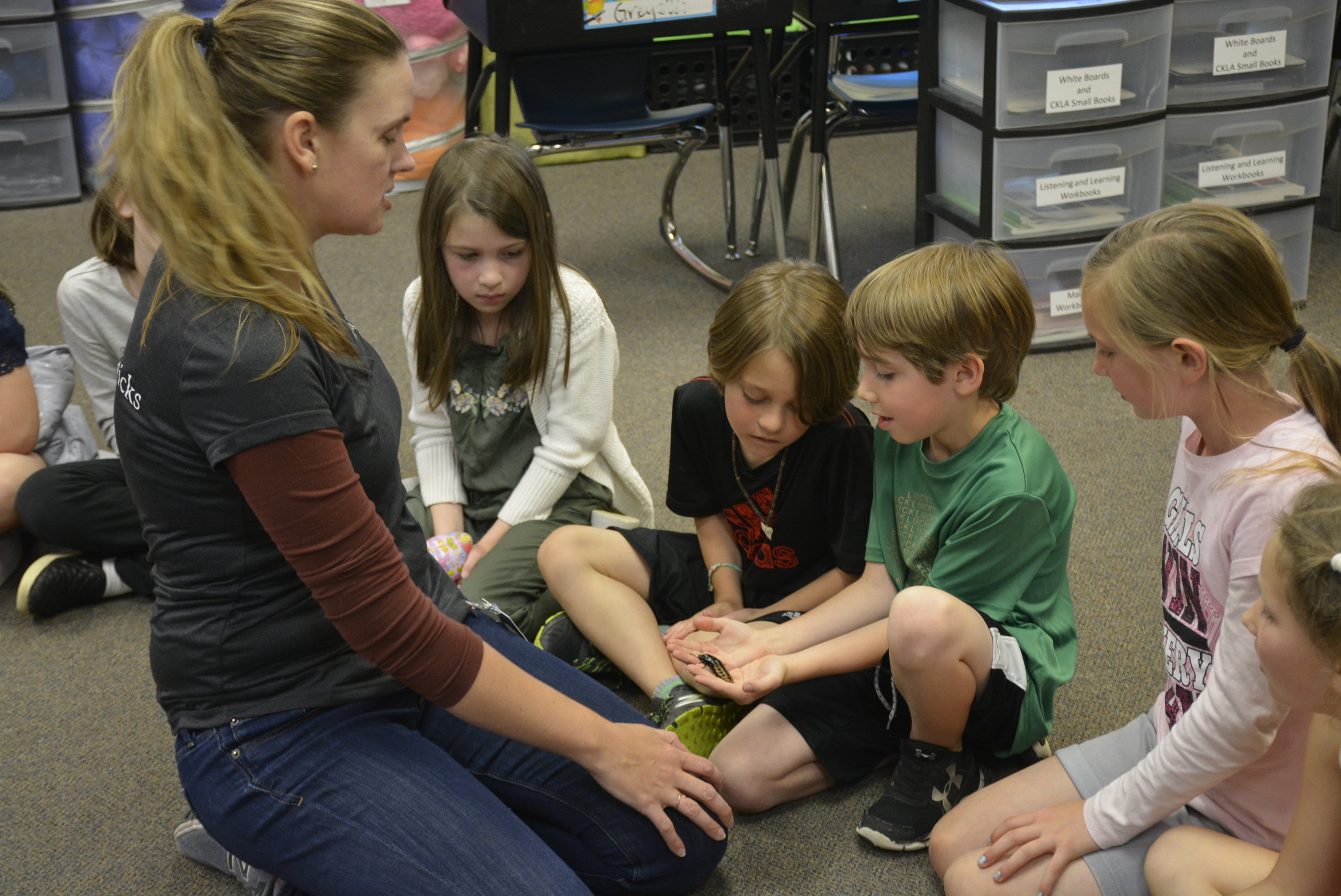 Entomologist Kristine Reddick hands an insect to a student and allows a student to touch it's back while other students look