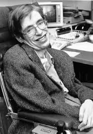 Stephen Hawkings seated at a desk with computer in background