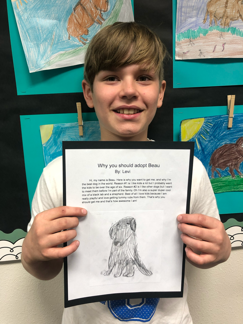 Student with paragraph and drawing of animal for adoption