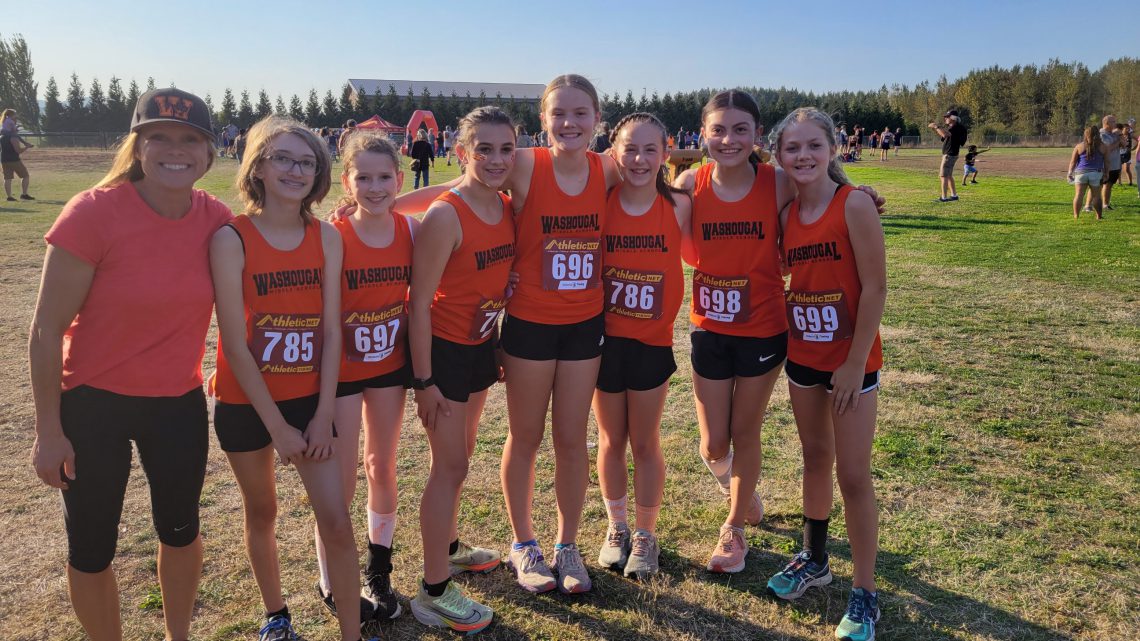 Washougal middle school Cross Country runners and coach Grice pose in front of the stadium