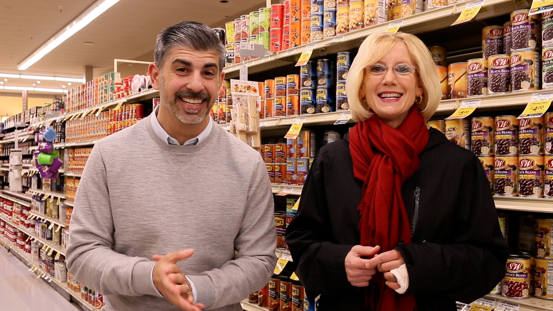 Camas Superintendent John Anzalone and Washougal Superintendent Mary Templeton smile, standing side-by-side in front of the canned food aisle at Safeway grocery store.