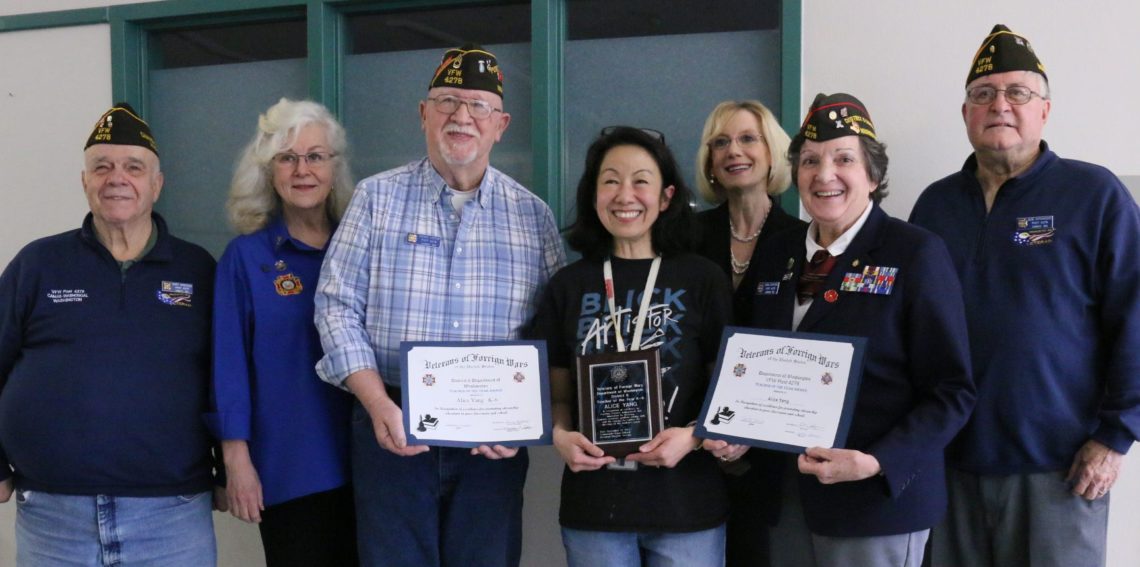 Alice Yang stands with 5 members of the VFW and the WSD superintendent with 2 awards and a plaque in hand