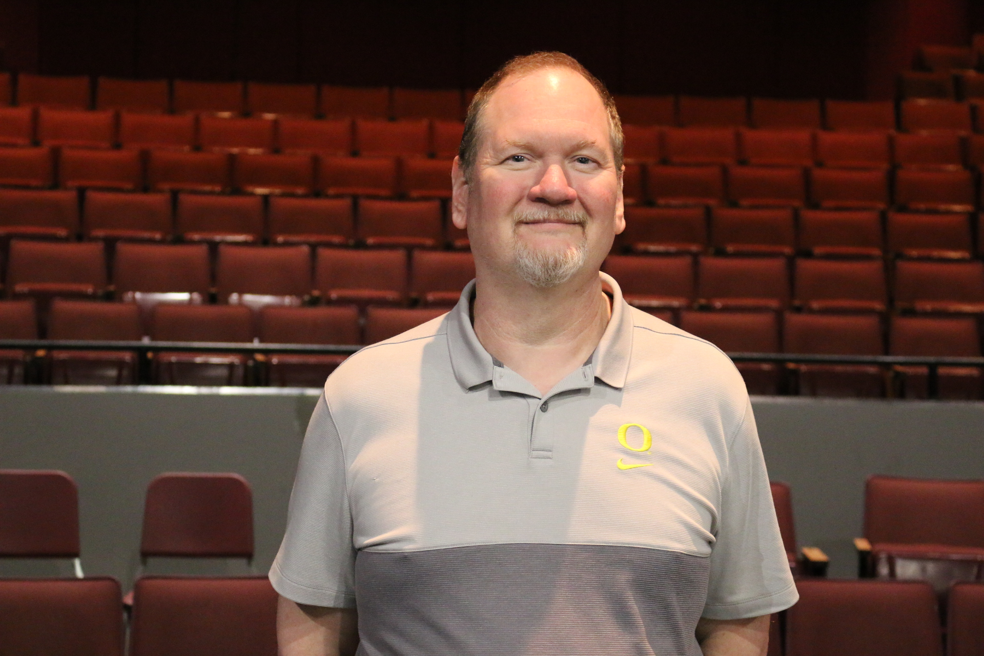 Man stands with auditorium seats behind him