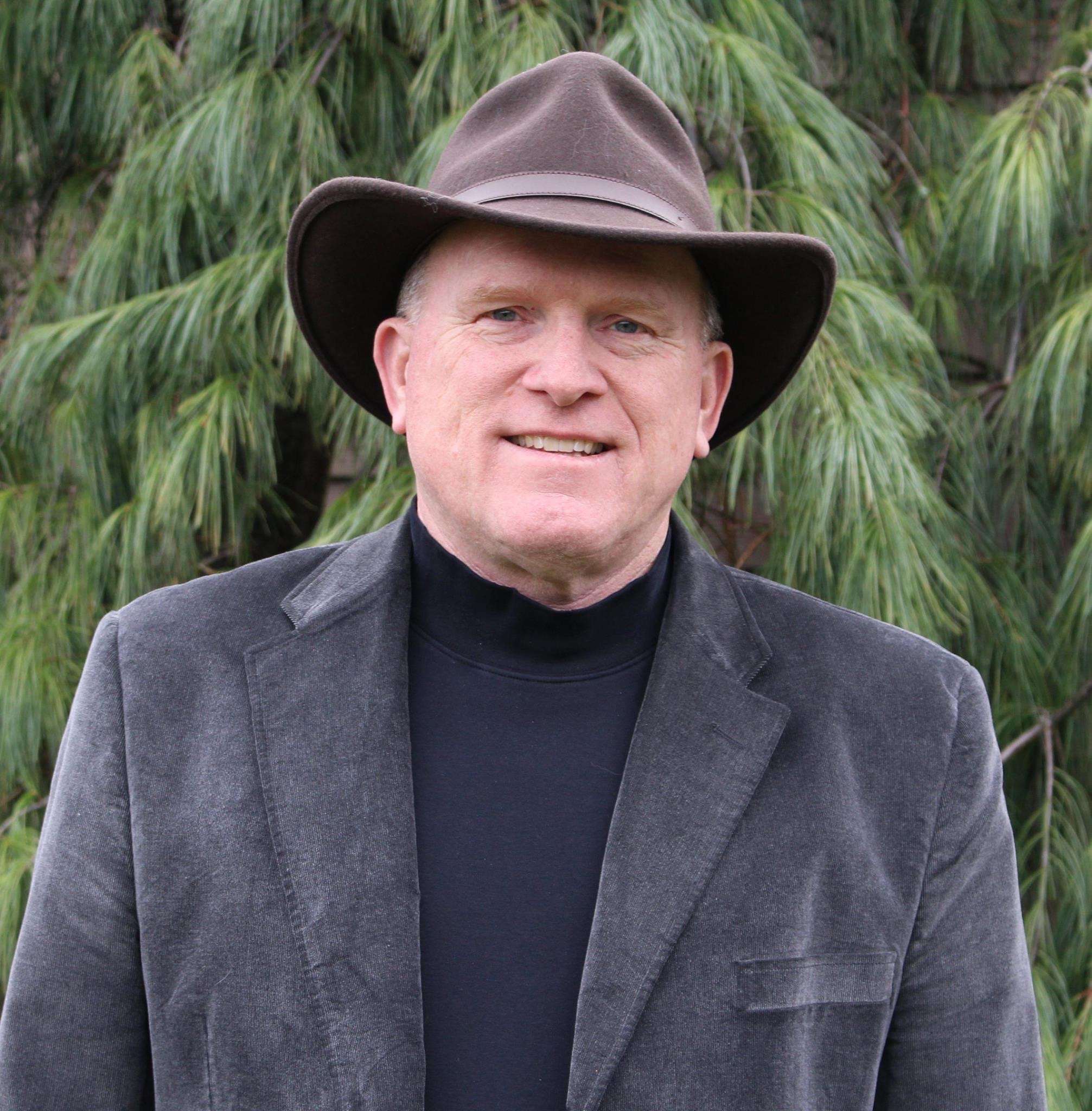 Roger standing in front of a tree, wearing a hat