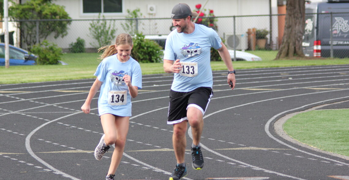 Student and parent running toward the finish line during the STRIDE fun run