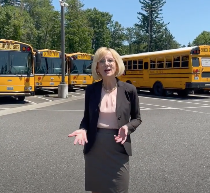 Mary in front of school buses thanking the community