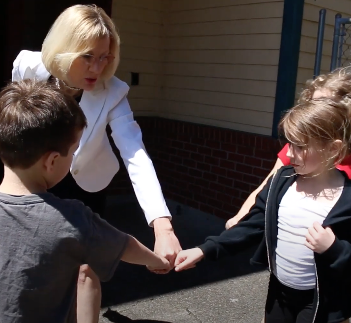 Students fist-bump with Mary on the playground