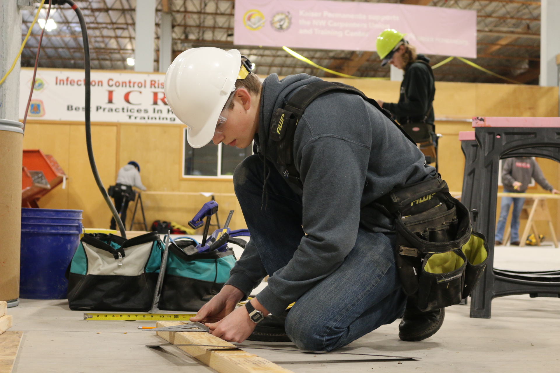 Student uses square to mark 2x4 during construction competition